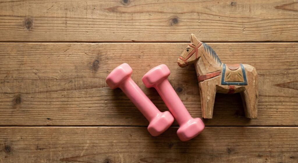 和風の板床に置かれたピンクのダンベルと、2026年の干支である午(うま)の木彫り民芸品