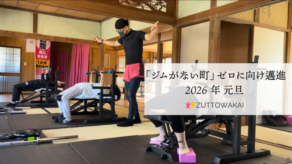 2026年元旦の挨拶。畳の和室にトレーニング機材を設置したジムで、ベンチプレスに励む人々と指導するトレーナーの様子。テキストには「『ジムがない町』ゼロに向け邁進」とあり、ZUTTOWAKAIのロゴが添えられている。